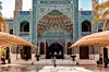 Ornate blue-tiled courtyard with arched entrances, covered walkways and palm trees.