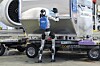 Humanoid robot lastar en JAL Cargo-container vid ett flygplans bagageområde.