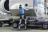 Humanoid robot lastar en JAL Cargo-container vid ett flygplans bagageområde.