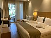 Valoisa hotellihuone, jossa parisänky, sohva ja näkymä parvekkeelle.