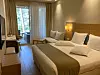Valoisa hotellihuone, jossa parisänky, sohva ja näkymä parvekkeelle.