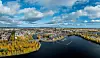 Ilmakuva Tampereen keskustasta, järvestä ja syksyisistä puista pilvisenä päivänä.