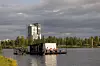 Saunalautta ja ihmisiä veden päällä Oulun edustalla pilvisenä päivänä.