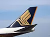 Bakre delen av ett Singapore Airlines-flygplan med guldfärgad logotyp mot blå himmel.