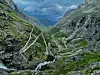 Snoet vej gennem en grøn fjelddal omgivet af stejle klipper og bjerge.