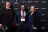 Kolme henkilöä poseeraa Grand Travel Awards -taustaseinän edessä.