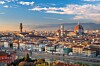 Udsigt over Firenze med byens tage, klokketårne og den røde domkirke under en blå himmel.