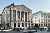 Klassinen historiallinen rakennus Kööpenhaminassa aukion laidalla, edessä polkupyöriä ja muutamia ihmisiä.