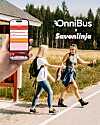 Kaksi naista kävelee tien reunassa bussipysäkin ohi, ja etualalla näkyy kädessä pidettävä älypuhelin OnniBus-sovelluksella.