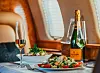 Dukat bord i ett privat jetplan med champagneflaska, glas, sallad och fönster i bakgrunden.