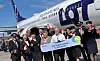 Grupp av flygbolagets personal står framför ett LOT-passagerarflygplan och håller en jubileumsskylt.