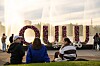 Suuri Oulu-tekstitaideteos aukiolla, ja muutama ihminen seisoo sen edessä iltavalossa.