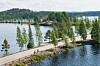 Järven rannalla kulkee tie puiden ja kivisen niemekkeen ohi, taustalla metsäistä maisemaa.