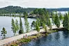 Järven rannalla kulkee tie puiden ja kivisen niemekkeen ohi, taustalla metsäistä maisemaa.