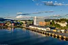 Vy över en kuststad med ett stort hotellbygge vid kajen, vatten i förgrunden och berg i bakgrunden.