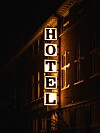 Pystysuora valaistu HOTEL-kyltti rakennuksen seinässä pimeässä.