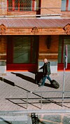 Mies vetää kahta matkalaukkua hotellin punaisen julkisivun edessä jalkakäytävällä.