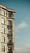 Korkea vaalea hotellirakennus, jossa on parvekkeita, näkyy sinistä taivasta vasten.
