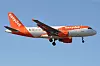 Ett orangevitt Easyjet-flygplan flyger lågt mot en blå himmel med landningsställ nedfällt.