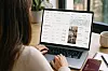 En person sitter vid en bärbar dator som visar sökresultat och resealternativ från Google Flights och Google Hotels.