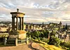 Utsikt över Edinburgh i Skottland från Carlton Hill med ett stenmonument i förgrunden och stadens byggnader i fjärran.