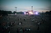 Laaja festivaalikenttä ja lava, jonka edessä ja ympärillä on paljon ihmisiä hämärässä.