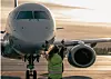 Ett passagerarplan på en flygplats med en person i reflexväst framför nosen.
