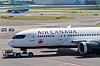 Air Canadan matkustajakone lentoaseman asematasolla, taustalla kiitotie ja rakennuksia.