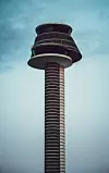 Korkea pyöreä torni kohoaa keskellä kuvaa pilvistä sinistä taivasta vasten.