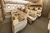 Lentokoneen Premium Economy -matkustamo, jossa on vaaleita nahkaistuimia ja leveä käytävä.