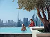 Uima-allas ja kaksi ihmistä Dubai skyline -pilvenpiirtäjien edustalla.