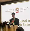 Mies puhuu mikrofonilla puhujakorokkeella Suomen ja Arabiemiirikuntien lippujen edessä.