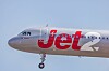 Jet2-matkustajakone vaaleansinisellä taivaalla, laskuteline näkyvissä.