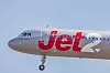 Jet2-matkustajakone vaaleansinisellä taivaalla, laskuteline näkyvissä.