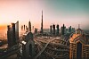 Dubain pilvenpiirtäjiä ja monitasoisia liikenneväyliä lämpimän iltataivaan alla.