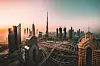 Dubain pilvenpiirtäjiä ja monitasoisia liikenneväyliä lämpimän iltataivaan alla.