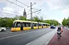 Keltainen raitiovaunu kulkee Turun kadulla pyöräilijän rinnalla; taustalla näkyy tuomiokirkko.