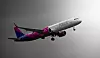Ett Wizz Air-passagerarflygplan flyger genom luften mot en grå bakgrund.
